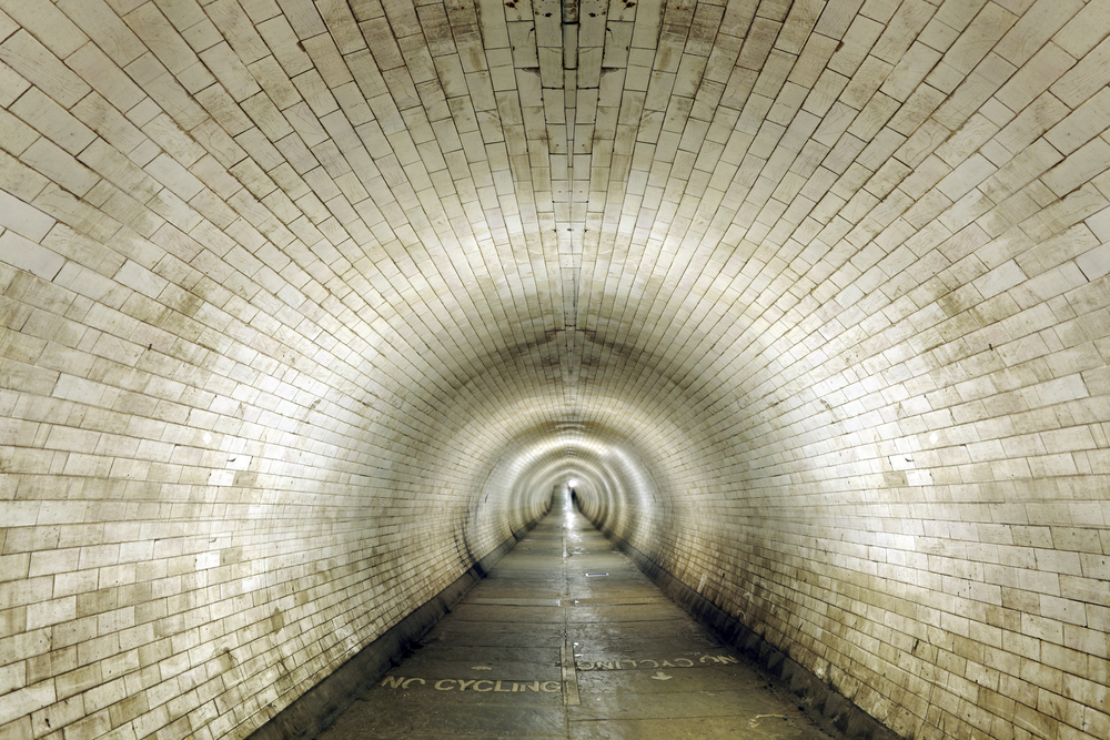 Entrance into a long vintage sepia stone mason tunnel.